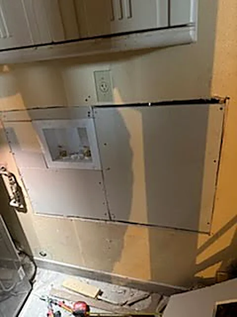 Drywall patch around a laundry connection in progress